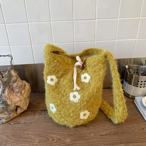 Detalle de bolso tipo saco de punto mostaza con motivos florales y cordón ajustable