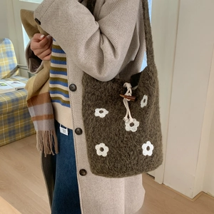 Detalle del bolso de hombro de punto con patrón de flores blancas y cierre de madera