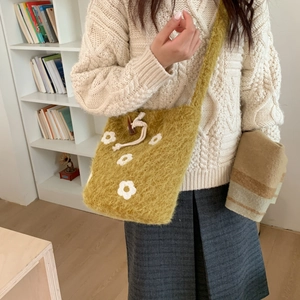 Detalle de bolso de punto amarillo con flores blancas y cierre de cuerno de buey