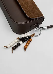 Detail of dark brown leather and suede texture with a stylish wooden beaded charm
