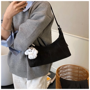Détail d'un sac hobo noir avec surpiqûres et un charmant petit chien en peluche