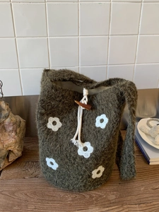 Bolso saco de felpa verde oliva con bordados de flores blancas y cierre de trenca