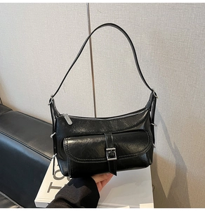 Detail view of black leather shoulder bag with silver hardware and front flap pocket