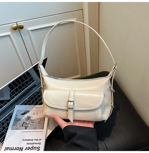 Close-up of beige leather shoulder bag with silver buckle pocket in an office setting