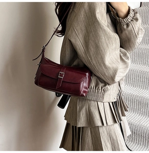 Detail view of burgundy vintage underarm bag with silver buckle and polished leather texture