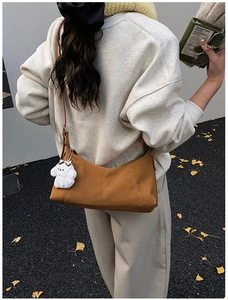 Détail du sac à bandoulière en cuir marron avec charme de chiot et coutures décoratives