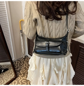 Detailed back view of a black retro pillow bag with adjustable strap and metal buckle pocket