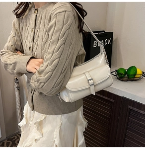Detail of cream white leather pillow bag with stylish buckle pocket and zip closure