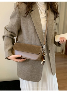 Detail view of tan suede leather baguette bag with a vintage wooden bead charm pendant