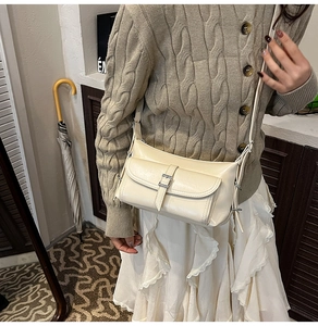 Detail view of a cream leather pillow bag featuring a silver buckle and front flap pocket