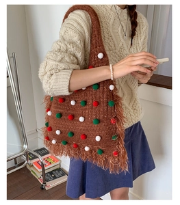 Detailansicht der braunen Strick-Tote-Bag mit bunten Pompons und Fransenverzierung