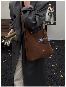 Détail du cabas en faux suède marron foncé avec logo blanc et accessoire mode