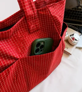 Vista detallada del bolso tote a cuadros rojos con un práctico bolsillo lateral exterior