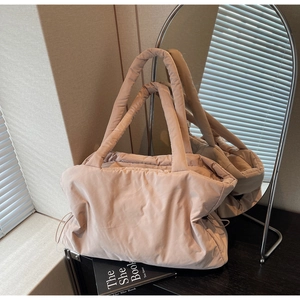 Detalle de un bolso tote de nailon acolchado en beige cálido sobre una mesa de madera oscura