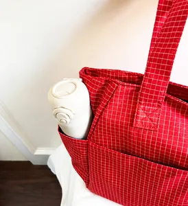 Detalle del bolso de cuadros rojos mostrando el bolsillo lateral con una botella de agua