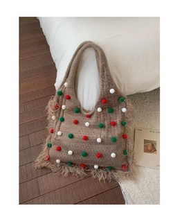 Nahaufnahme der braunen Stricktasche mit bunten Pompons und langen Fransen-Details