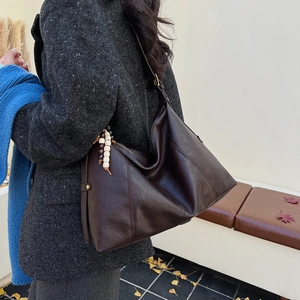 Detail of deep brown large tote bag with bohemian beaded tassel and stitching accents