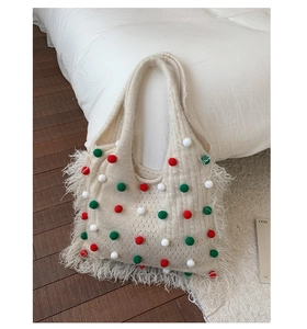 Nahaufnahme cremefarbene Stricktasche mit festlichen Bommeln und Fransen Details