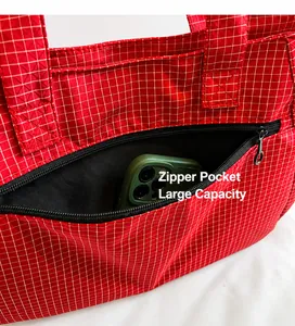 Detalle de un bolso tote de cuadros rojos con bolsillo con cremallera para móvil