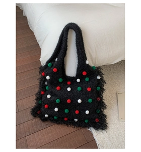 Gros plan d'un sac cabas noir en peluche avec pompons colorés et détails de franges