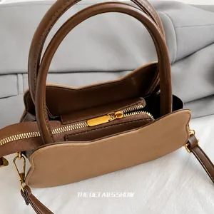 Dettaglio della cerniera in metallo dorato e cuciture della borsa in ecopelle marrone