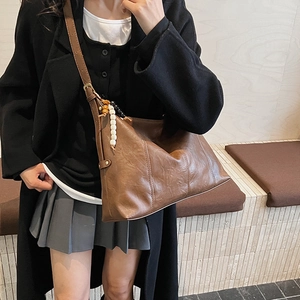 Brown vintage faux leather tote bag with wooden bead tassel and crossbody strap detail