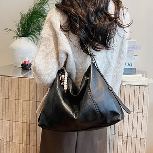 Detail of black Hobo tote bag with decorative tri-color beads on model in cozy winter style