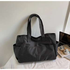 Detalle del bolso tote gris de cuadros con bolsillo lateral y accesorios