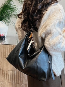 Large black leather tote bag for women with decorative wooden bead handle and minimalist style