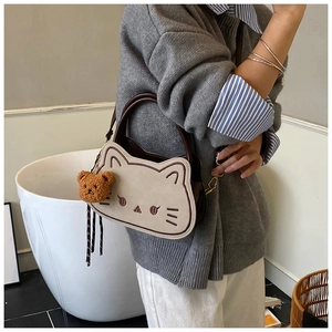 Vista dettagliata di una borsa a forma di gatto beige con un ciondolo a orsetto marrone