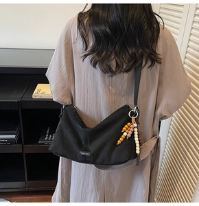 Detail van de zwarte nylon hobo-tas met zilveren beslag en kleurrijke houten kralenhanger