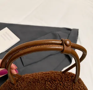 Detail showing the brown plush texture and sturdy leather handle with stitching