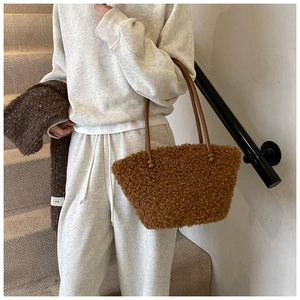 Detail view of brown plush tote bag with slim dark leather handles and sphere accents