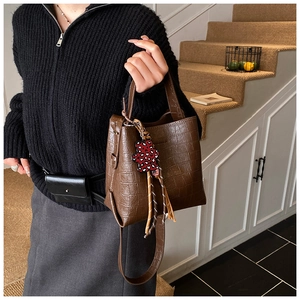 Brown crocodile embossed bucket bag with leopard bear charm shown on a model