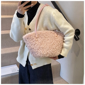 Close-up of pink fuzzy plush handbag with slender leather straps on a knit cardigan