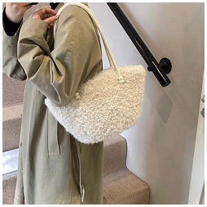 Detail of soft white plush tote bag with slim shoulder straps styled with khaki trench coat