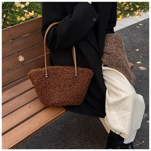 Brown plush tote bag with wooden ring handles shown in an outdoor lifestyle setting