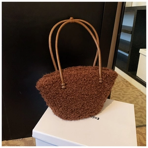 Detail of dark brown plush handbag featuring soft faux fur texture and slim leather handle