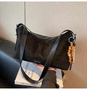 Detail van zwarte suède hobo tas met kleurrijke houten kralen en zilveren ritssluiting