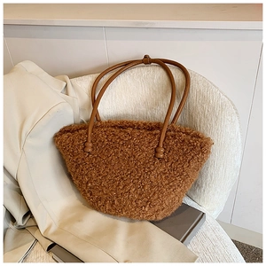 Close-up of brown plush faux fur tote bag with round handle on a soft textured chair