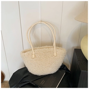 Close-up of cream fuzzy plush handbag featuring elegant beaded handle details in soft lighting