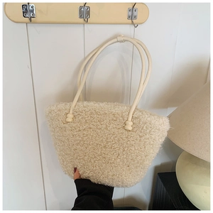 Close-up of fluffy cream-white plush tote bag with thin faux leather straps and ball buckles