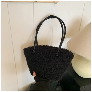 Detailed macro view of soft black plush faux fur material and beaded handle of the tote bag