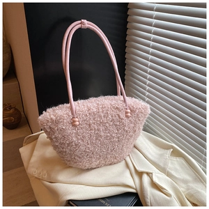 Detail of pink faux fur shoulder bag with tubular strap resting on a beige blazer