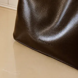 Λεπτομέρεια macro της σκούρας καφέ δερμάτινης τσάντας με ανάγλυφο λογότυπο και υφή
