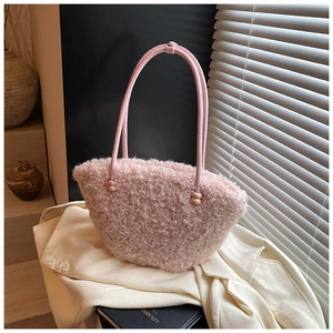Close-up of fluffy pink faux fur tote bag with leather handle on white blazer
