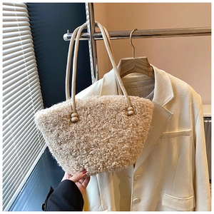 Detailed close-up of a beige faux shearling tote bag with soft texture and slim handles
