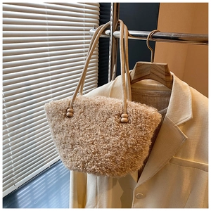 Detail of soft cream plush tote bag with decorative beads hanging on a wooden hanger