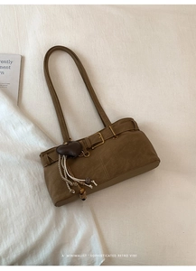 Detail van vintage bruine schoudertas met hartvormige hanger op lichte stoffen ondergrond