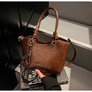 Détail du sac à main en cuir mat marron avec poignée à nœuds et breloque en corde